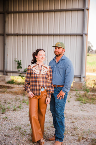 Full outfit view of the CORE Blue long sleeve pearl snap shirt with jeans and brown boots, alongside a woman in plaid.