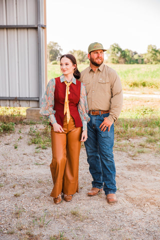 Model in the CORE Khaki long sleeve pearl snap shirt with jeans and boots beside a woman in a red vest and brown pants.