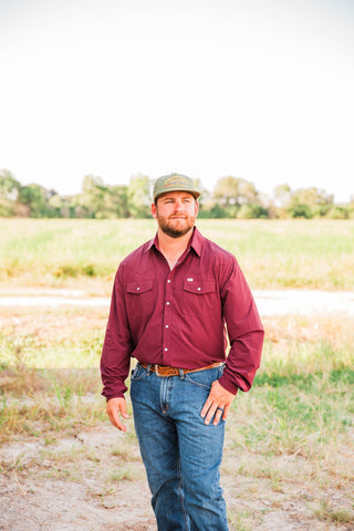 Front view of the CORE Maroon long sleeve pearl snap shirt with two flap chest pockets, styled with blue jeans.