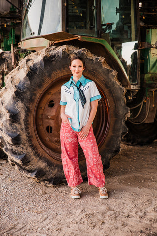 Pink Desert Bandana Western Barrel Jeans paired with a white and turquoise Western shirt, black neck scarf and sneakers.
