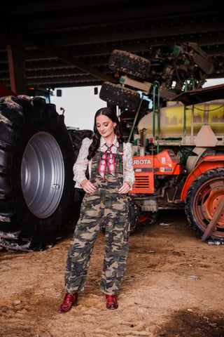 Women’s camouflage barrel overalls styled with Western shirt, cowboy boots and statement jewelry