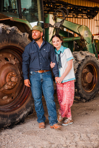 Full-length couple portrait showing the Silas black patterned pearl snap by Ferrell tucked into jeans with a brown belt and boots.