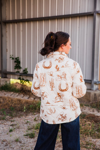 Back view of the cream Frontier Jacket, showing brown Western prints of cowboy boots, horseshoes, cacti and riders.