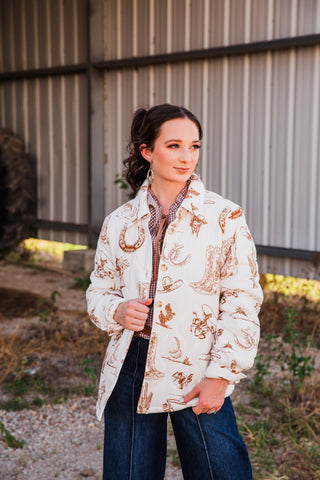 Frontier Jacket in cream with brown cowboy boot, horseshoe and cactus prints, worn open over a gingham blouse and jeans.