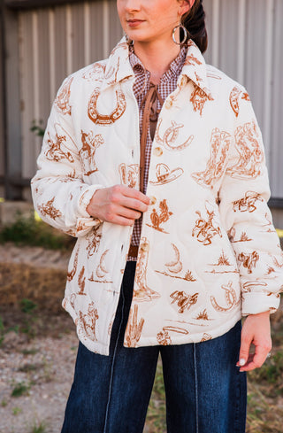 Close-up of the Frontier Jacket showing its pointed collar, button front and brown cowboy boot and horseshoe print on cream.