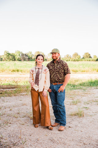 Full outfit view of the Gage Camo pearl snap shirt with jeans and brown boots, modeled beside a woman in a Western outfit.