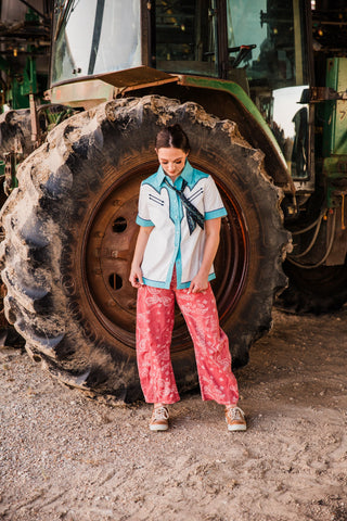 Full-length look at the Hold Your Horses black Twilly paired with a pearl snap shirt, pink paisley pants and tan sneakers.