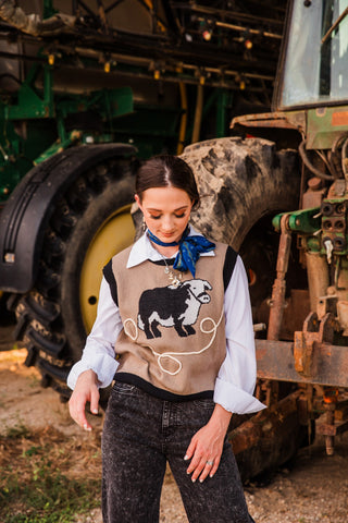 Hold Your Horses Navy Twilly worn as a side neck bow with a tan bull knit vest, white blouse and washed black jeans.