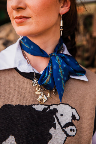 Hold Your Horses Navy Twilly tied in a neck bow, showing turquoise diamond motifs and small starburst patterns over a white collar.
