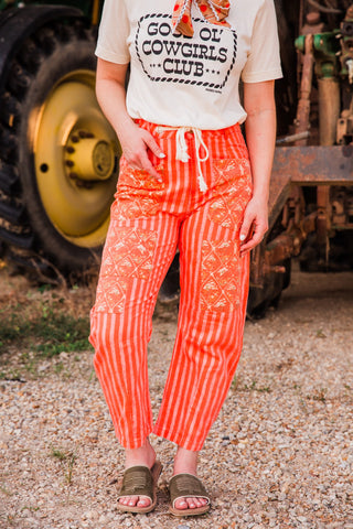 Everyday Outlaw Pants by Howdy Hanny with red-orange and cream stripes, patterned patch panels and a cream drawstring waist.