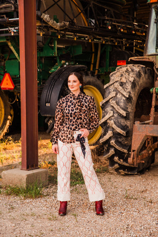Penny leopard print top by Howdy Hanny styled with cream rope-print pants and red ankle boots beside a tractor.