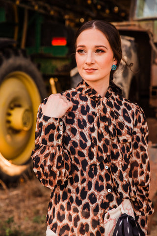 Close-up of the Penny leopard print top by Howdy Hanny, highlighting its wide button cuff, gathered sleeve and tied neckline.