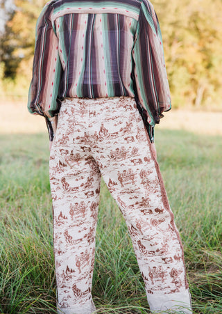 Back view of Howdy Hanny Ranch Life Barrel Jeans showing brown ranch scenes on cream denim, back pockets and rolled hems.