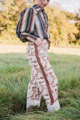 Side profile of Howdy Hanny Ranch Life Barrel Jeans highlighting the curved leg shape, brown side trim and cream cuffed hems.