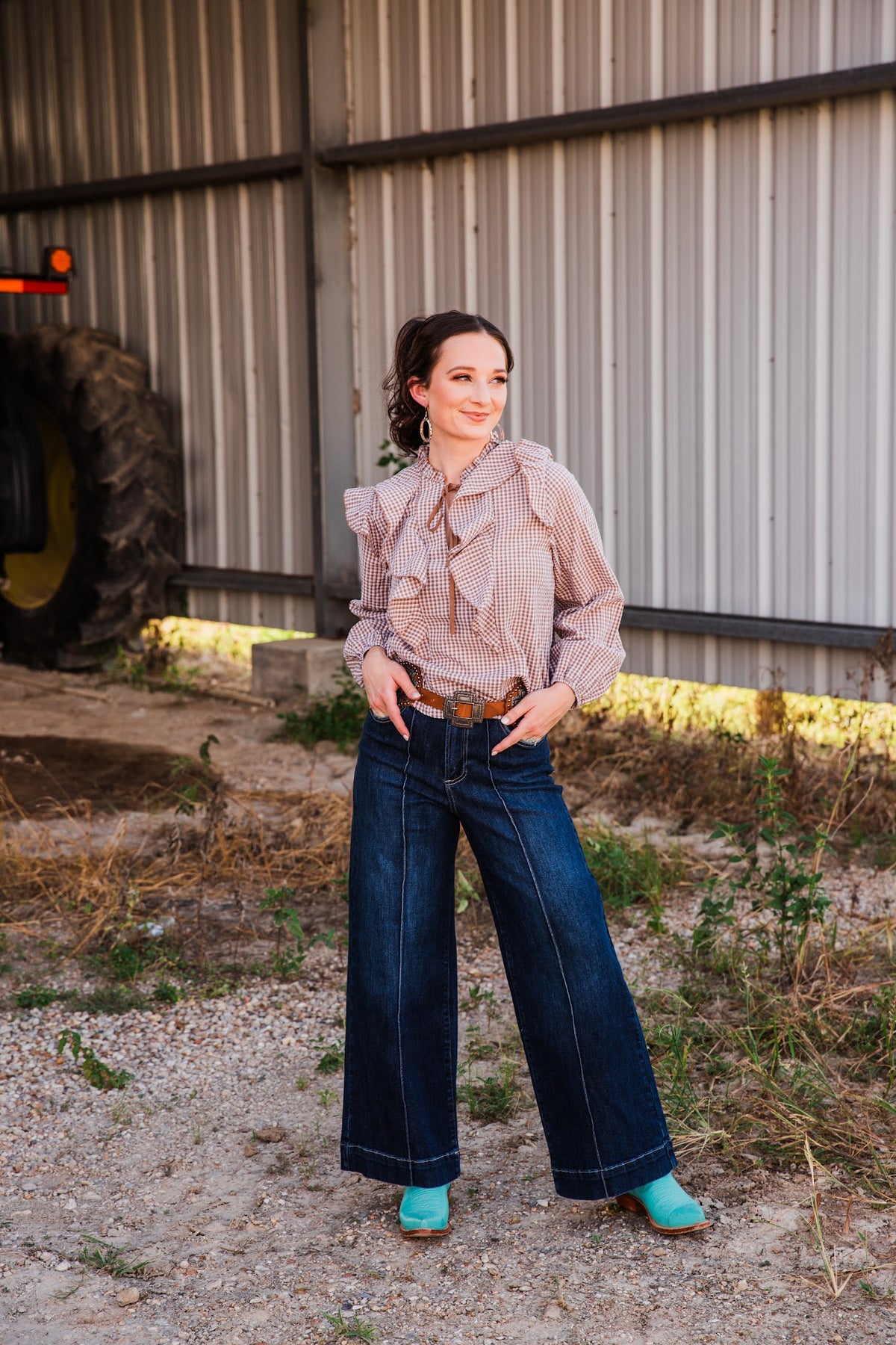 Jincy Top brown gingham ruffle blouse styled with wide-leg dark jeans, a brown belt and turquoise cowboy boots.