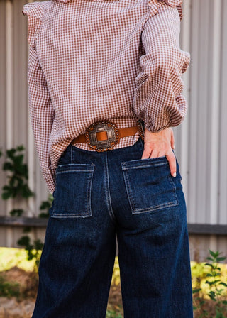 Back detail of the Kaufman tan leather belt, showing an ornate rectangular metal concho with a studded leather border.