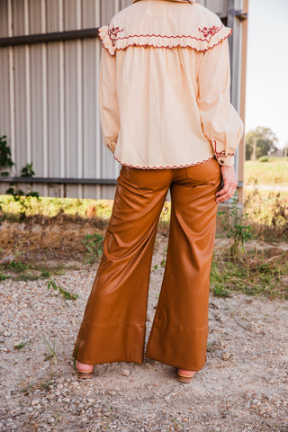 Back view of Lee caramel brown faux leather pants, showing rear patch pockets, wide legs and a smooth, subtly shiny finish.