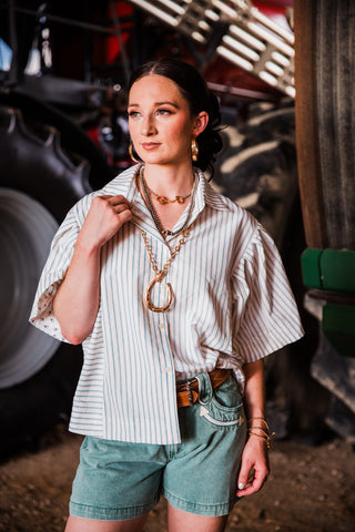 The Outlaw striped seersucker shirt styled with Western jewelry, denim shorts and cowboy boots