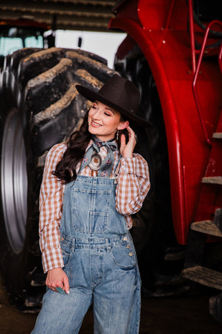 Cowgirl Classic women’s Western pearl snap blouse styled with denim overalls and cowboy hat