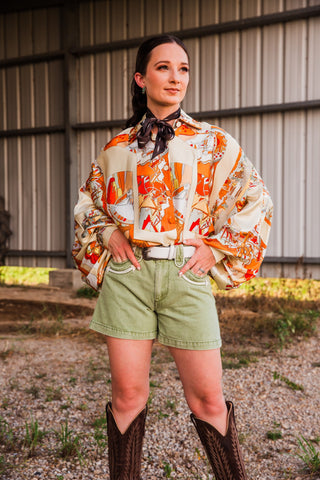 Polly Olive Shorts by Howdy Hanny styled with an orange and cream Western print blouse, white belt and tall brown boots.