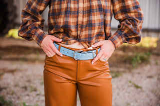 Powder blue suede belt by Double J Saddlery with a silver-tone buckle, styled with a brown plaid shirt and caramel pants.