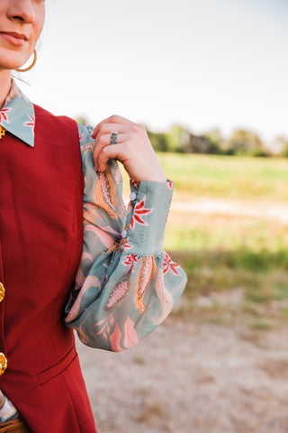 Sage Paisley Blouse sleeve close-up showing a wide cuff with pale buttons and gathered fabric in pink, peach and red print.