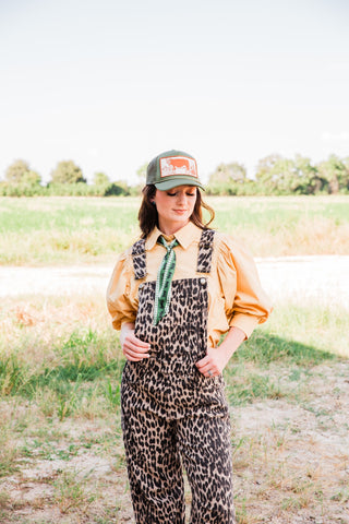 Front view of the Savannah leopard print jumpsuit showing its bib pocket and hip pockets, layered over a buttercream blouse.