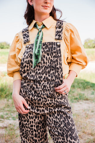 Close front view of the Savannah leopard print jumpsuit highlighting the chestnut pattern, bib pocket, and curved hip pockets.