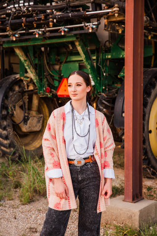 Front view of the Sedona Ruffle Tie Top in White, with cascading ruffles and cuffs visible beneath a pink floral cardigan.