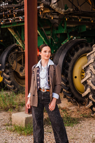 Sedona white ruffle tie blouse styled beneath a brown Western blazer with washed black jeans and a silver-tone belt buckle.