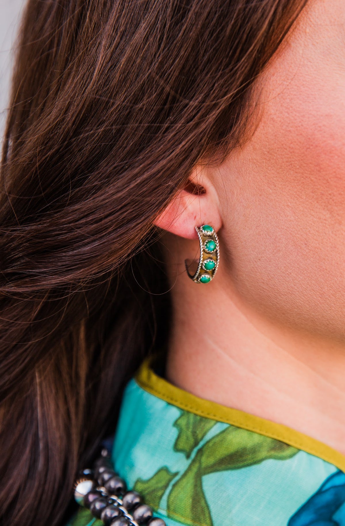 Side view of a Sonoran Trail #2 green turquoise hoop earring, showing round stones along the curved sterling silver hoop.