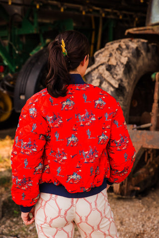Back view of the Southern Cowboy Bomber Jacket with an allover red cowboy and cactus print, navy collar and ribbed waistband.