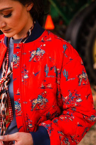 Close-up of the Southern Cowboy Bomber Jacket showing diamond quilting, riders on horseback, cactus motifs and navy ribbed trim.