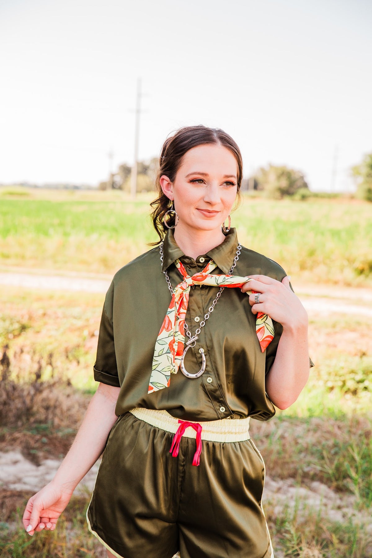 Model wearing Stamped Dangle Hoop Earrings with an olive satin set, citrus neck scarf and silver-tone horseshoe necklace.