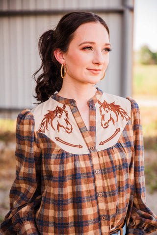 THML plaid horse blouse close-up showing brown horse and arrow embroidery on a cream yoke with brown, tan and blue plaid.