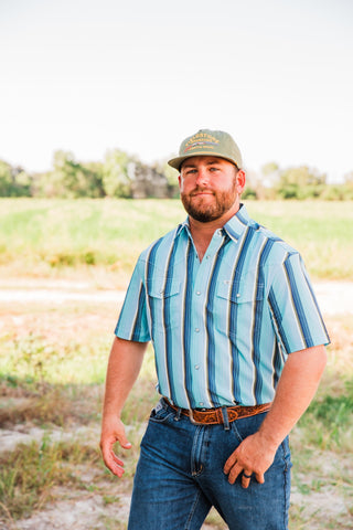 Front view of the Tristan blue striped short sleeve pearl snap shirt with two flap chest pockets, styled with jeans.