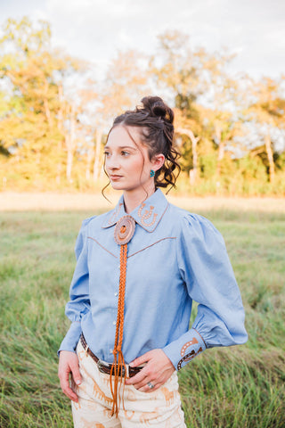 Turquoise Haven Lucky Trails chambray blouse showing horseshoe collar embroidery, contrast Western yoke piping and puff sleeves.