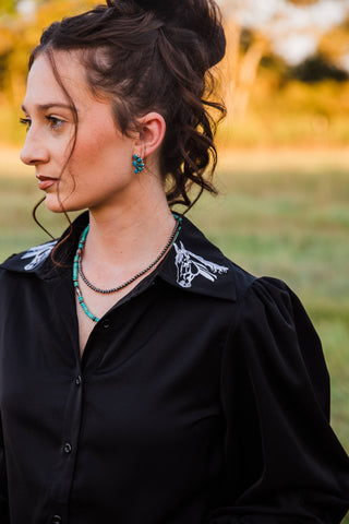 Midnight Rider blouse by Turquoise Haven, close-up of white horse embroidery on the black collar and gathered shoulders.