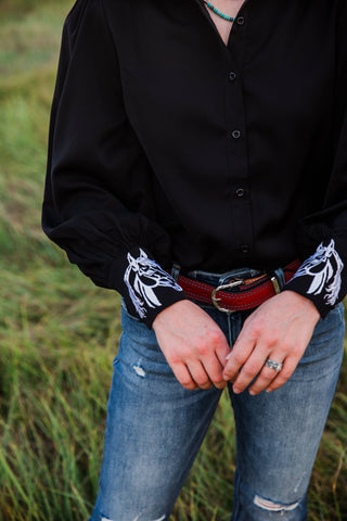 Turquoise Haven Midnight Rider blouse sleeve detail showing gathered black fabric and contrasting white horse-head cuff embroidery.