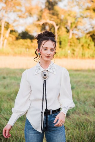 Wild Rein Bucking Horse Blouse by Turquoise Haven, front view of white fabric, embroidered collar and long gathered sleeves.