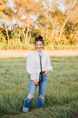Full-length front outfit with the white Turquoise Haven Wild Rein Bucking Horse Blouse, embroidered cuffs and cuffed blue jeans.