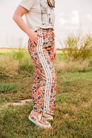 Side view of the Duck Camo Lace Trim Pants showing three white lace bands running down the outer leg and a side pocket.