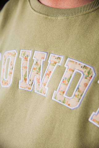 Close-up of the green HOWDY Oversized Sweatshirt showing Western-print letters with cactus motifs, stitched borders, and crewneck.