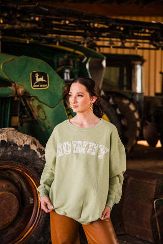 Sadie in size S/M of the green HOWDY Oversized Sweatshirt, showing dropped shoulders and a long hem over brown pants.