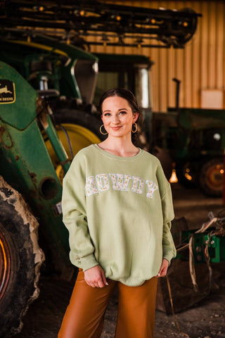 Sadie styles the green Varsity Rodeo HOWDY Oversized Sweatshirt in size S/M with brown pants and gold hoop earrings.
