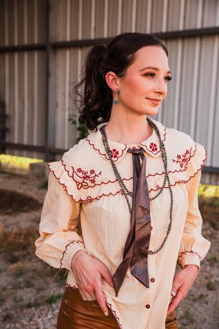 Winchester Top close-up showing burgundy floral embroidery on the cream ruffled yoke, scalloped edges and matching buttons.