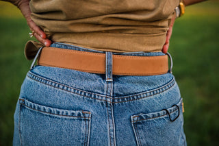 Back view of the Wrangler Mommy + Me Belt showing a smooth tan strap with stitched edges threaded through blue jeans.
