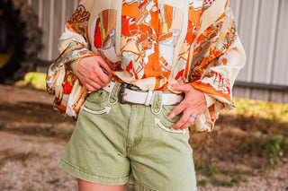 Wrangler Mommy + Me white Western belt styled with olive denim shorts and an orange and cream printed blouse.