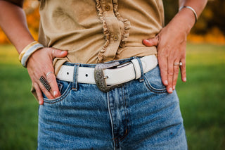 Wrangler Mommy + Me white belt with an engraved silver-tone Western buckle, worn with blue jeans and a tan ruffled shirt.