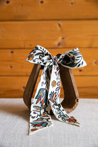 XOXO Art & Co Ink in Bloom ivory silk twilly with pointed tails, multicolor floral artwork, leafy stems and black detailing.